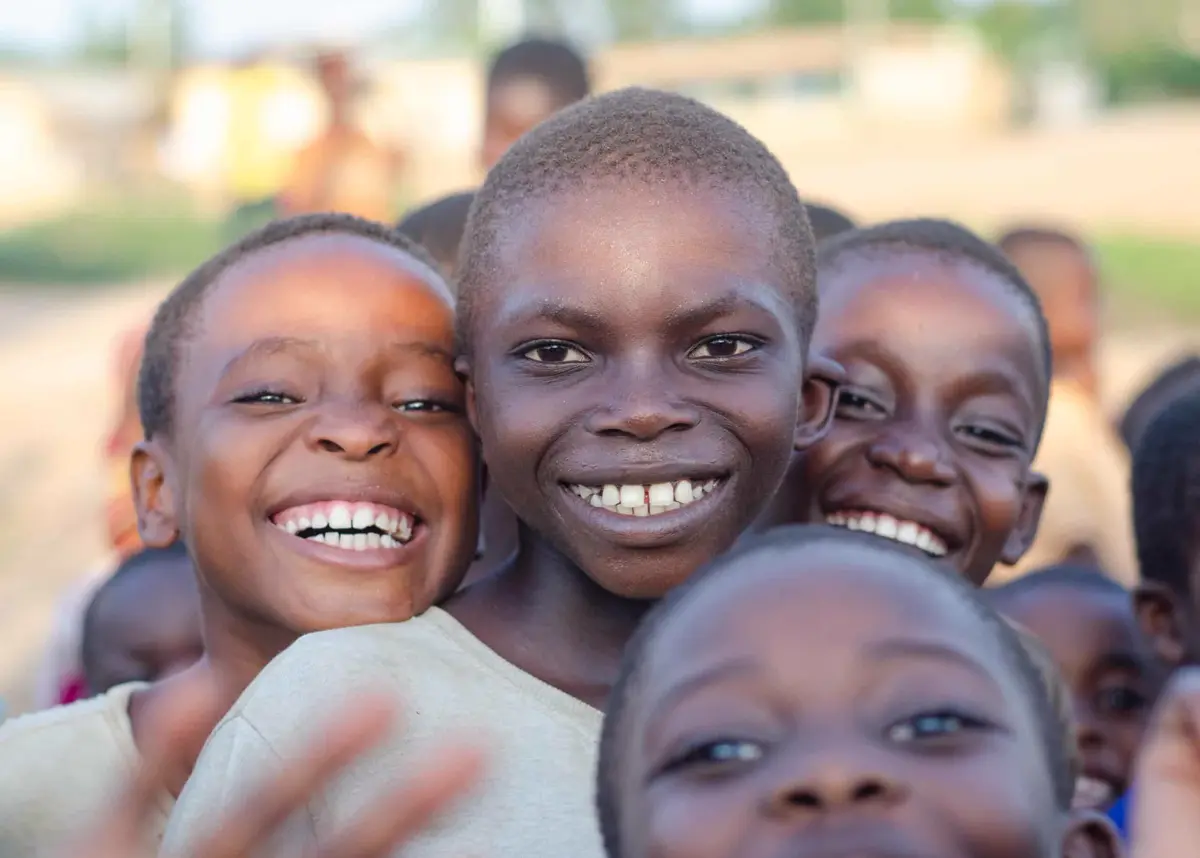 A group of laughing children crowd together for the camera